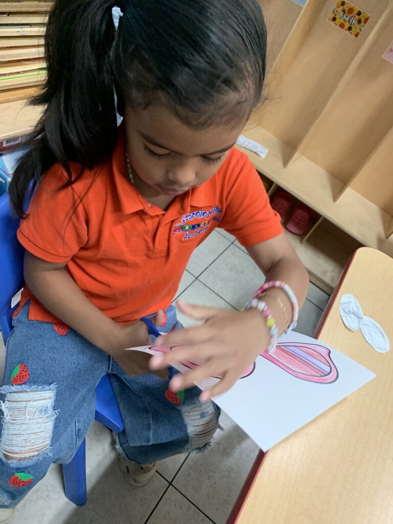A young Learningville student practicing cutting skills on a paper craft